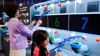 Nintendo Museum visitors playing a grabbing game inspired by Nintendo's classic Ultra Hand toy.